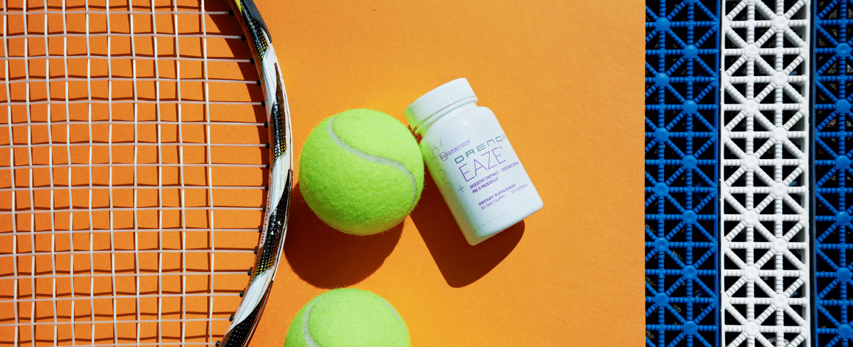 bottle of Orenda Eaze laying flat next to two tennis balls and tennis racquet