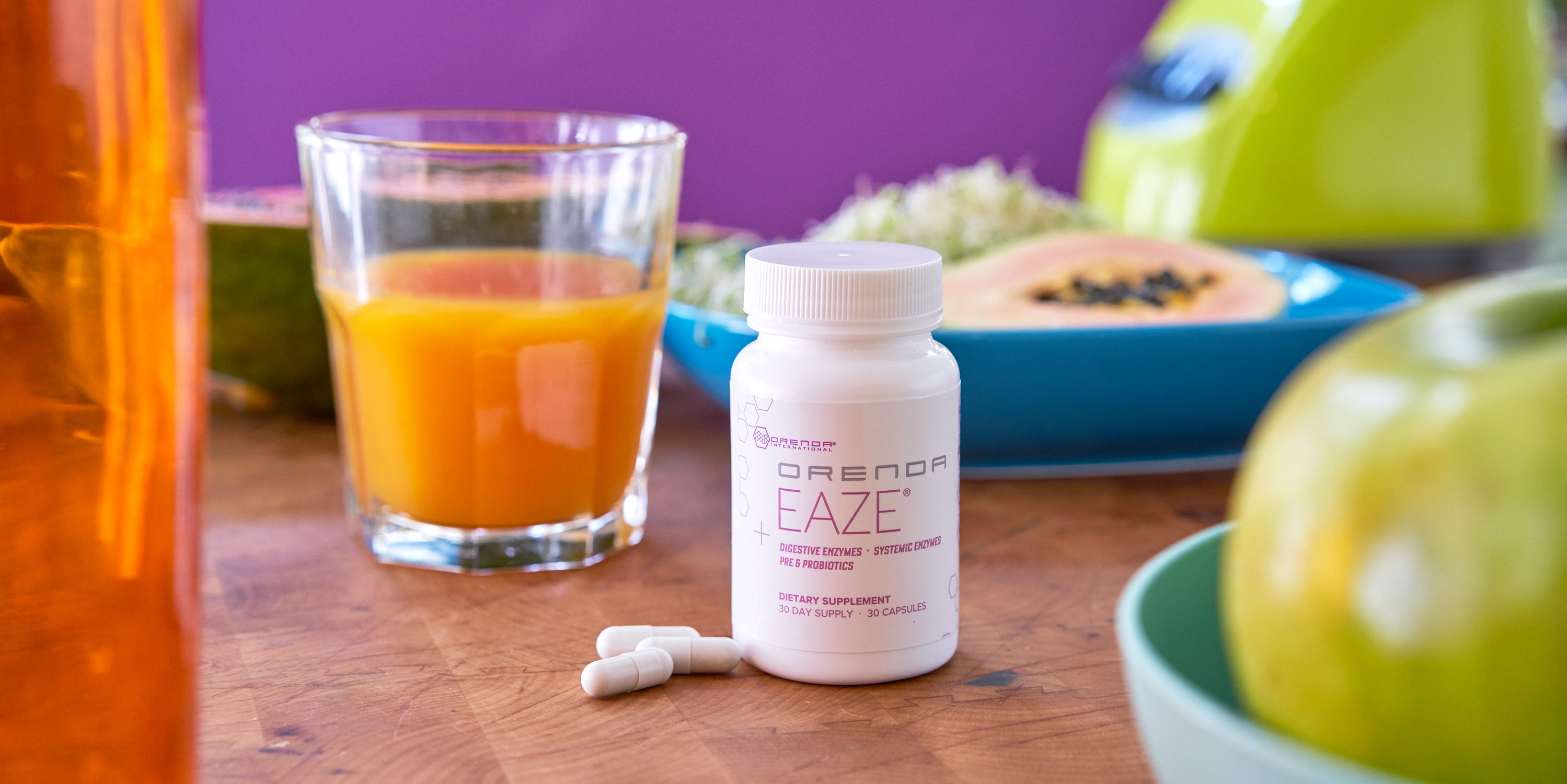 Bottle of Eaze with three capsules on a wood table by glass of orange juice