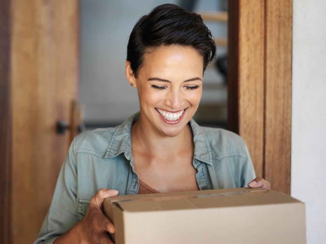 Woman holding package in door smiling