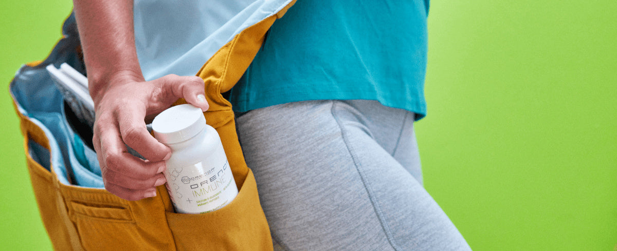 Woman with gold messenger bag on her hip pulling Orenda Immune bottle from the bag