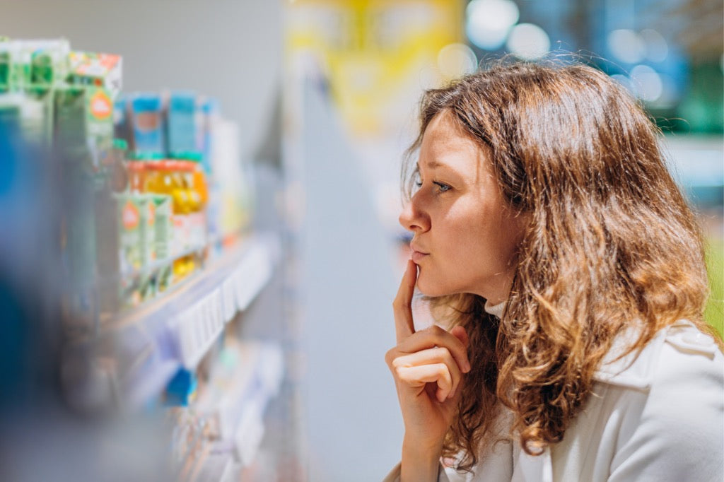 woman looking at store shelf of supplement bottles trying to make a decision